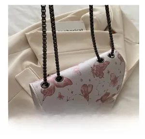 Détail du sac à chaîne blanc avec imprimé papillon rose et anneaux métalliques foncés