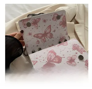 Gros plan sur le sac à rabat en cuir blanc avec imprimés papillons roses et boucle aimantée