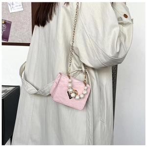 Pink pearl-beaded handbag with gold heart charms worn over a beige trench coat