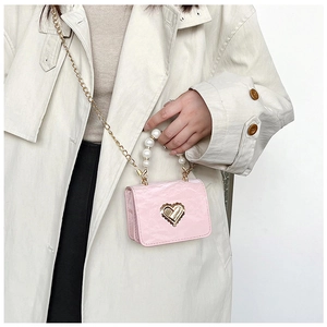 Detailed shot of pink heart-lock mini bag with oversized pearl handle and gold chain