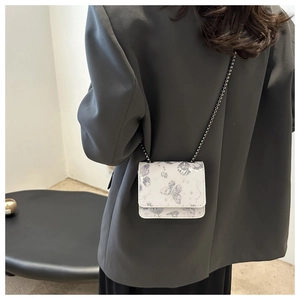Détail du mini sac à rabat blanc avec motifs papillons gris et fine chaîne en métal