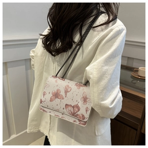 Detail of elegant butterfly print on beige leather bag with stylish metal chain strap