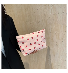 Close-up of pink corduroy handbag with strawberry pattern and zipper detail