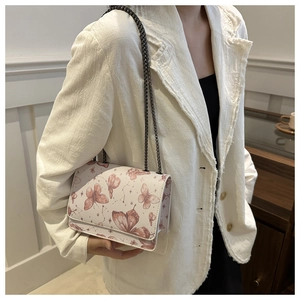 Detail of trendy creamy white square bag with red butterfly print and metal chain strap