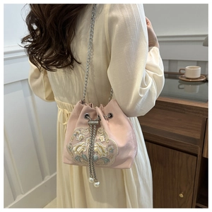 Detailed view of pink silk bucket bag with floral embroidery and pearl chain strap