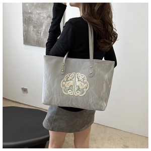 Close-up of a grey tote bag with elegant floral embroidery and textured finish