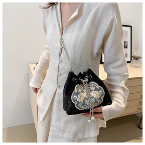 Detail of floral embroidery and pearl drawstring on black velvet bucket bag
