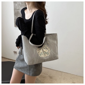 Detail of grey tote bag featuring intricate Chinese floral embroidery and nylon texture