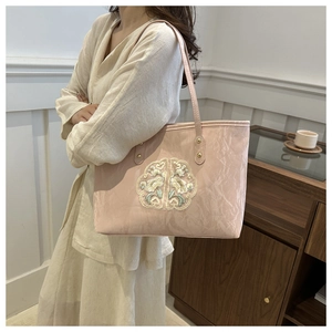 Gros plan sur la broderie florale d'un sac cabas rose élégant en similicuir avec anses