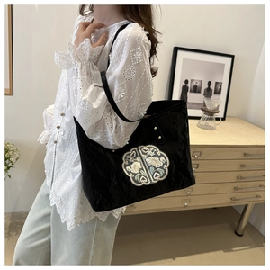Détail du sac cabas en velours noir avec broderie florale vintage et bandoulière en cuir