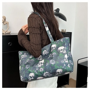 Detail of a tote bag with gothic skull and floral print worn by a model in a modern room