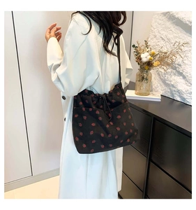 Model wearing a black canvas drawstring bag with strawberry prints for casual daily styling