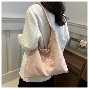 Detail view of pink wrinkled texture tote bag with silver triangle logo on model