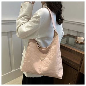 Detail of pink hobo bag with pleated texture and metallic triangular logo on the side