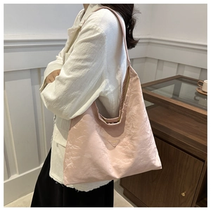 Dettaglio borsa hobo rosa in tessuto stropicciato con logo metallico triangolare