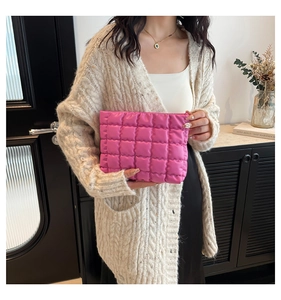 Détail d'une pochette matelassée rose vif tenue par un mannequin avec style chic