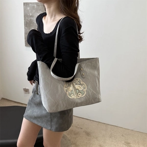 Grey tote bag with gold floral embroidery in modern Chinese style on female model