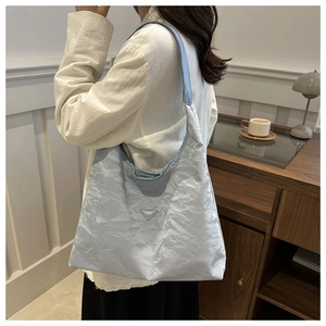 Detail of light blue wrinkled fabric tote bag with FASHION leather patch on model