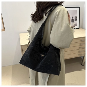 Dettaglio borsa hobo nera lucida a pieghe con targhetta metallica triangolare fashion