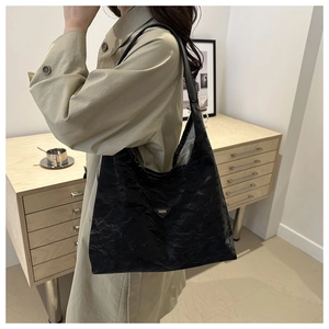 Dettaglio borsa tote nera in ecopelle stropicciata con logo metallico triangolare