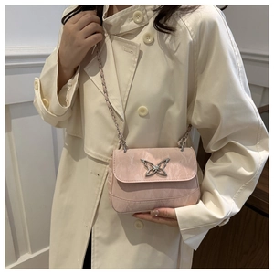 Close-up of pink chain bag with metal butterfly buckle worn with a beige trench coat