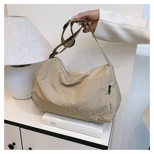 Close-up of beige nylon shoulder bag showing pleated texture and side zipper pocket