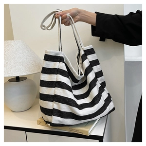 Detail shot of large capacity black and white striped canvas tote bag in a cozy home setting