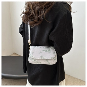 Detail of green butterfly print on white leather crossbody bag with gold hardware
