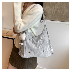 Détail du sac bandoulière plissé argenté avec boucles papillon et pendentif nuage doux