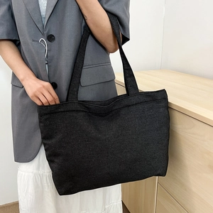 Large capacity black canvas tote bag for women shown with a stylish casual outfit