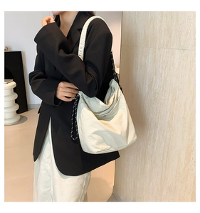 Close-up of off-white nylon hobo bag with decorative woven rope strap on model