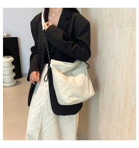 Close-up of cream nylon tote bag with black and white braided strap for modern fashion
