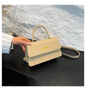 Close-up of beige lychee texture leather bag with Fashion lettering and handle