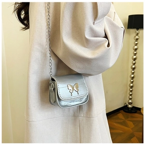Silver mini saddle bag with butterfly buckle and chain strap shown on model's shoulder