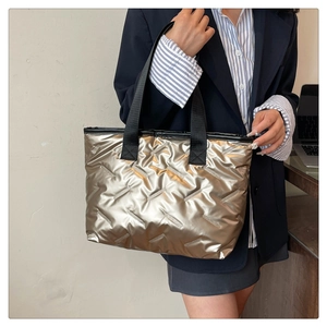 Close-up of champagne metallic tote bag with quilted diamond pattern and black straps