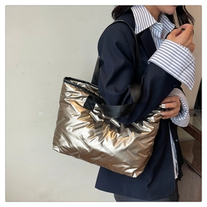 Fashionable champagne gold quilted tote bag with black strap held by a model in a suit