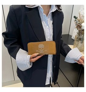 Close-up of brown suede long wallet featuring a sparkling rhinestone skull and crossbones