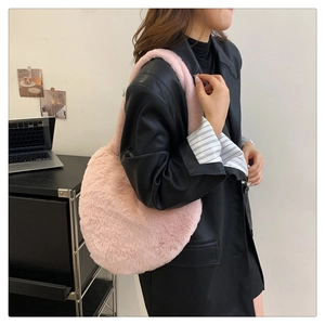 Détail d'un sac à bandoulière en fausse fourrure rose porté avec un blouson en cuir noir