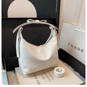 Détail du sac à main blanc brillant avec nœud décoratif et bandoulière réglable