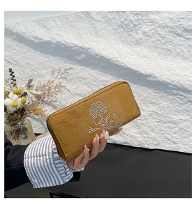 Detail of yellow long wallet with sparkling rhinestone skull and metallic zipper closure