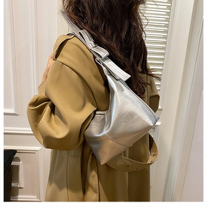 Détail du sac seau argenté métallisé avec nœud élégant sur un trench-coat chic