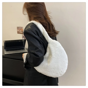 Gros plan d'un sac à bandoulière en fausse fourrure blanche porté sur une veste