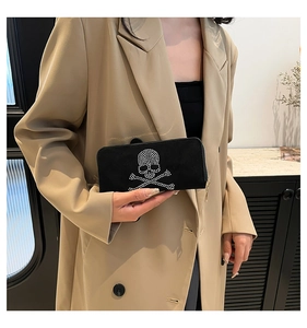 Detail of a black suede clutch featuring a sparkling rhinestone skull and crossbones