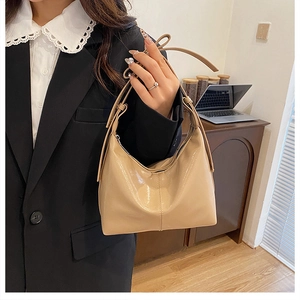 Détail d'un sac hobo en cuir brillant beige crème avec bandoulière réglable et fini lisse