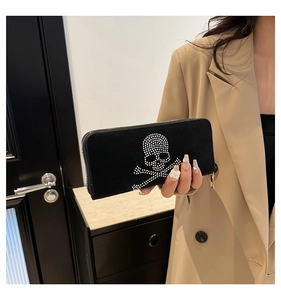 Detail of a black suede clutch bag featuring a sparkling rhinestone skull and crossbones