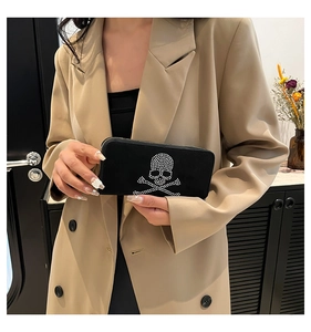 Detail of black suede clutch bag featuring sparkling rhinestone skull and crossbones motif