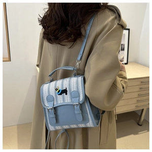 Detail of light blue striped backpack featuring dog embroidery and adjustable straps