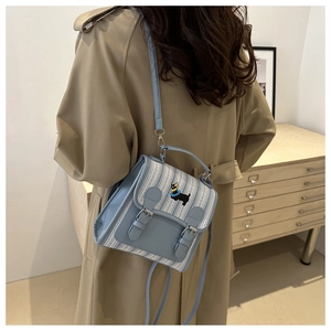 Rear view of model wearing a light blue striped crossbody bag with dog embroidery
