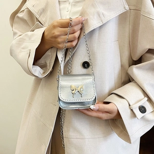 Mini silver butterfly chain bag in metallic leather for women on beige trench coat