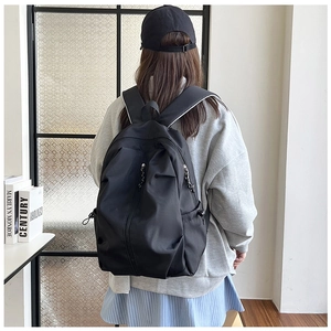 Detail of minimalist black backpack featuring dual front zippers and drawstring side pockets